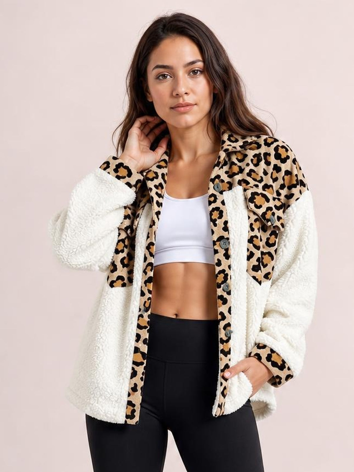 A model poses in a relaxed fuzzy button-up jacket with white sherpa sleeves, leopard-print panels, long sleeves, front buttons, and patch pockets.