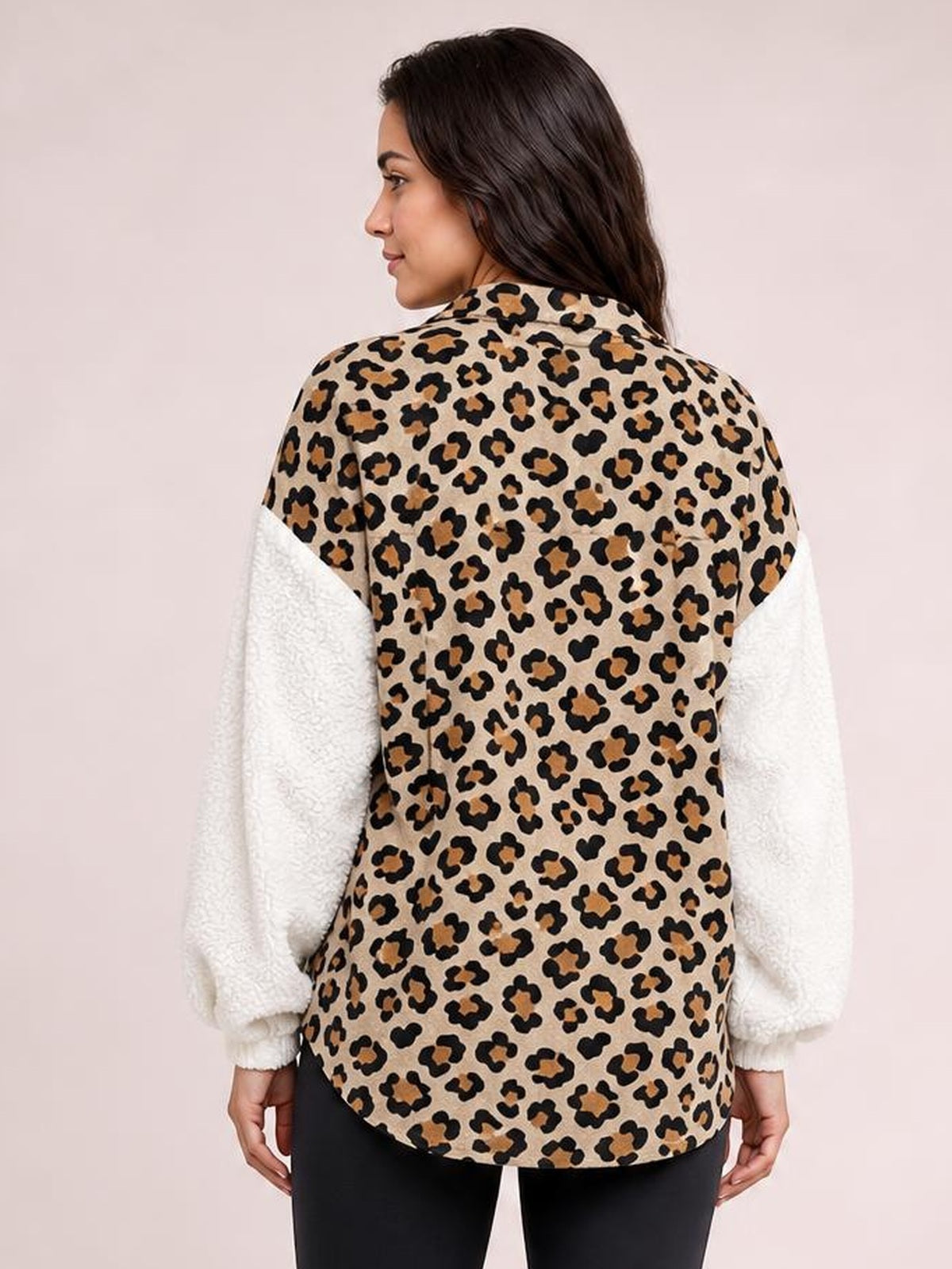A model faces away wearing a tan-and-black leopard-print fuzzy jacket with white plush long sleeves, a collar, and a relaxed longline silhouette.