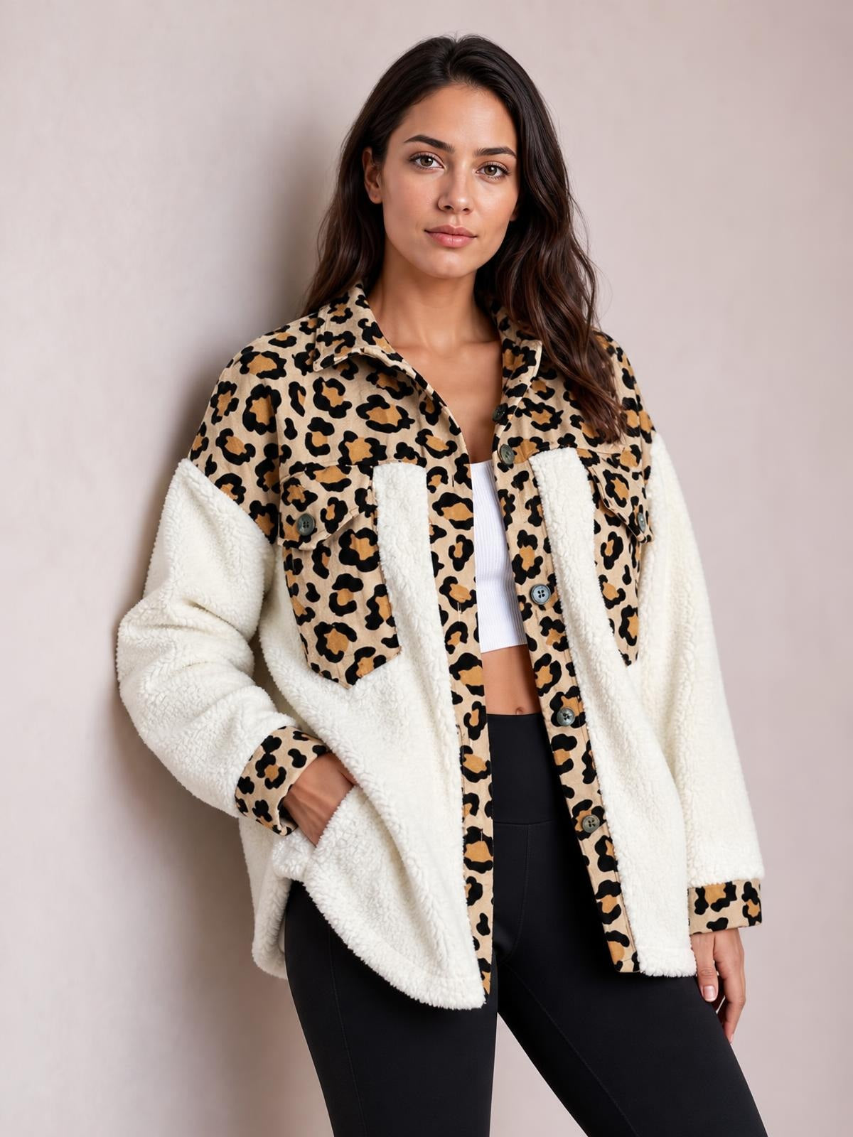 Woman standing with one hand in a pocket wears a thick cream fuzzy button-up jacket with long sleeves, leopard-print panels, collar, cuffs, and relaxed silhouette.