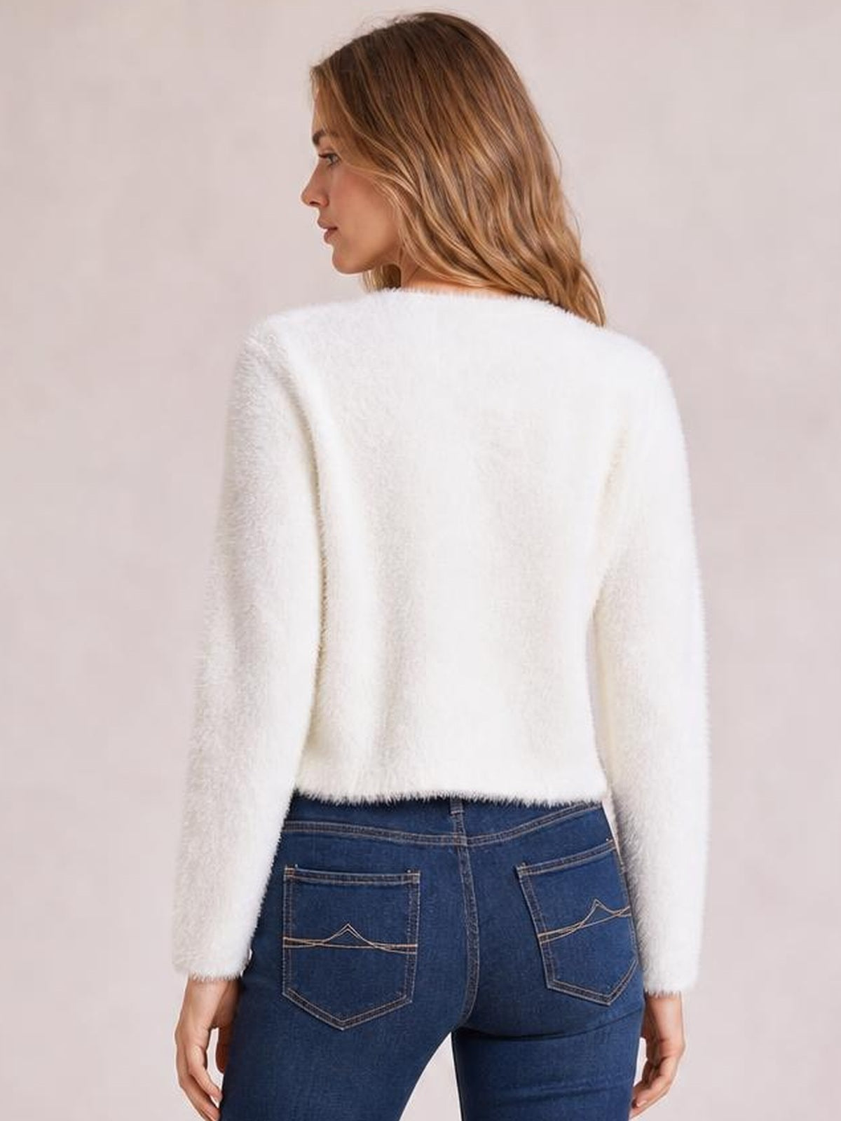 A model looks over her shoulder wearing a white fuzzy knit cardigan with long sleeves, a soft relaxed silhouette, and a straight hem.
