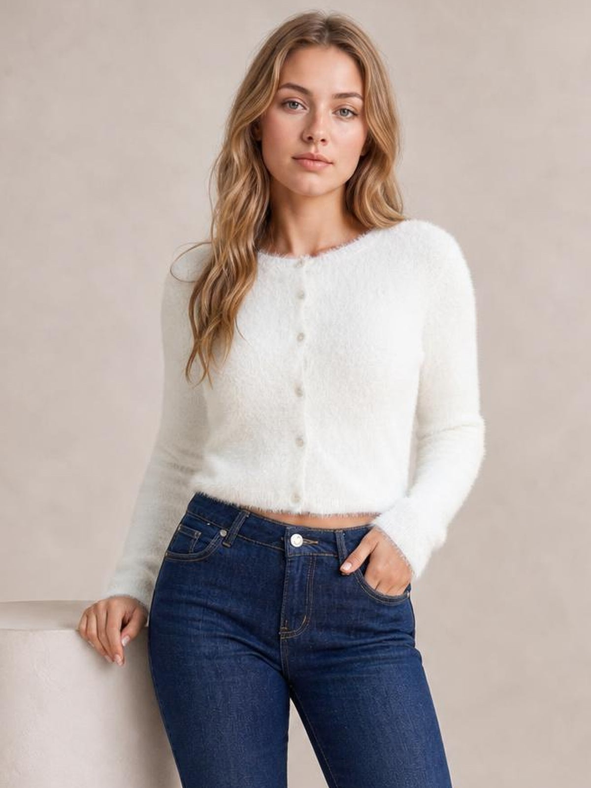 Model wears a white fuzzy knit button-down cardigan with a soft textured finish, long sleeves, round neckline, cropped silhouette, and front buttons.