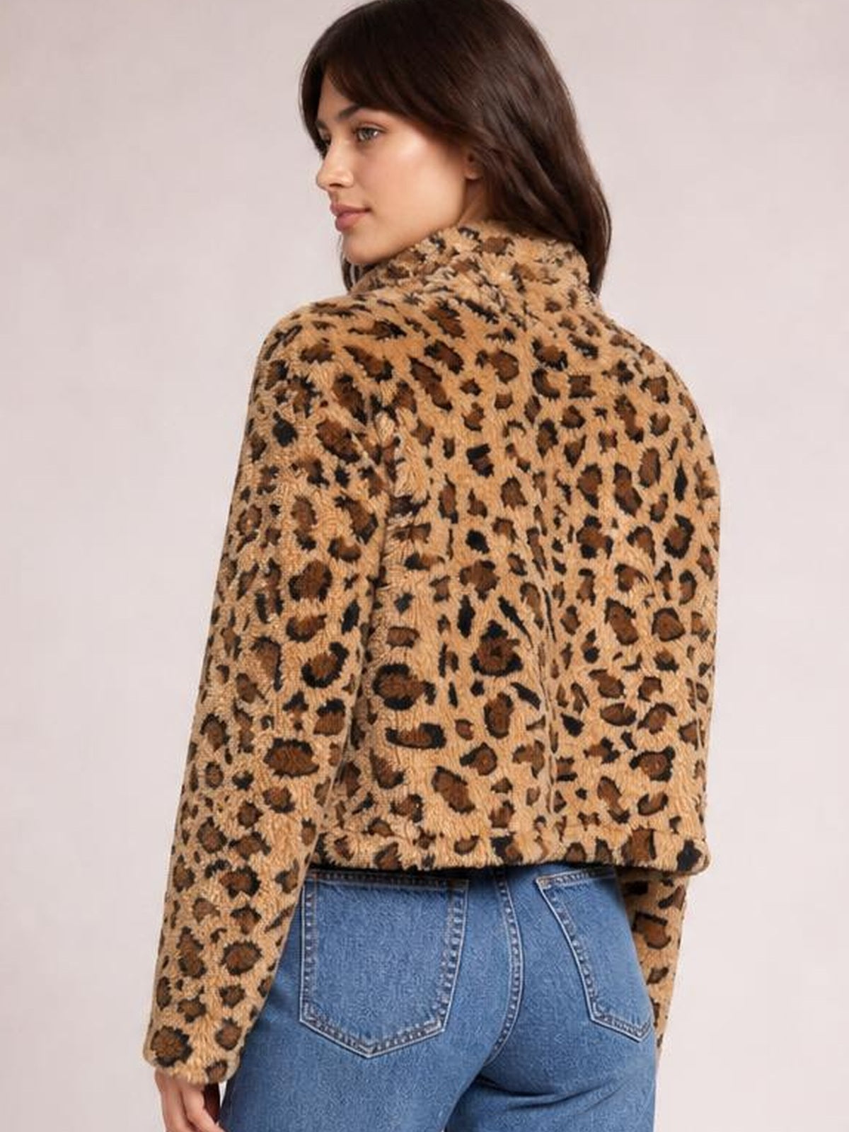 A model looks over her shoulder in a fuzzy tan-and-brown leopard-print turtleneck zip-up jacket with long sleeves and a relaxed cropped silhouette.