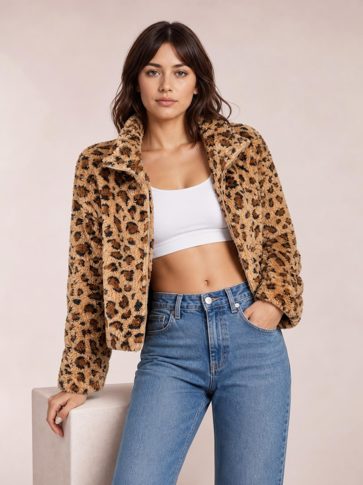 A model poses in a fuzzy tan leopard-print turtleneck zip-up jacket, worn open with a relaxed silhouette, one hand in her jeans pocket.