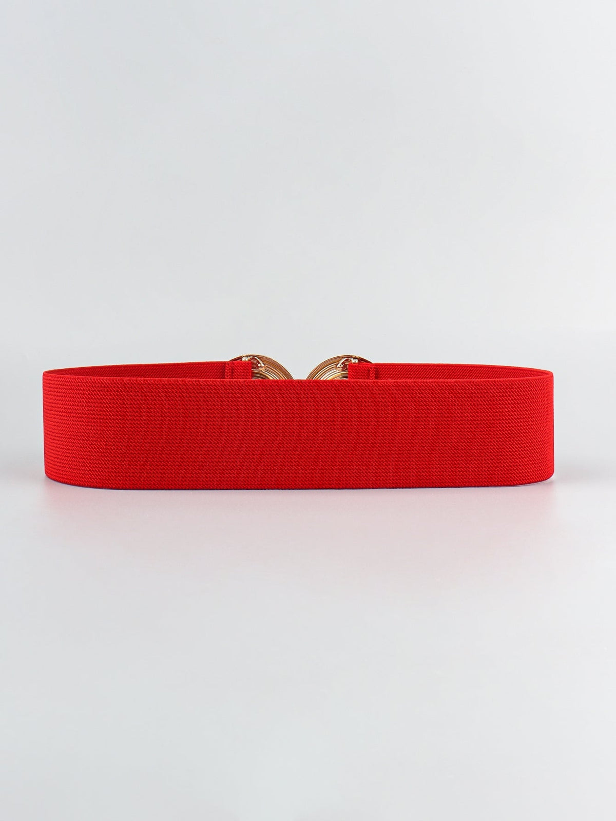 A red elastic wide belt with a broad woven band and a partially visible geometric alloy buckle featuring rounded interlocking forms.