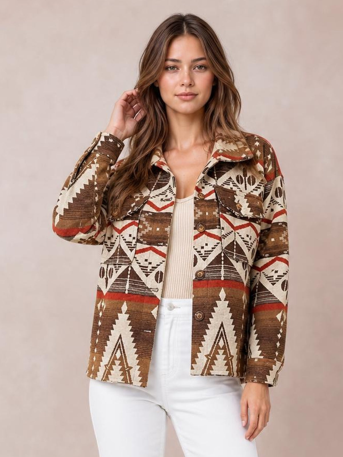 Model poses with one hand in her hair wearing a brown, cream, and red geometric button-up jacket with long sleeves, pockets, and a straight silhouette.