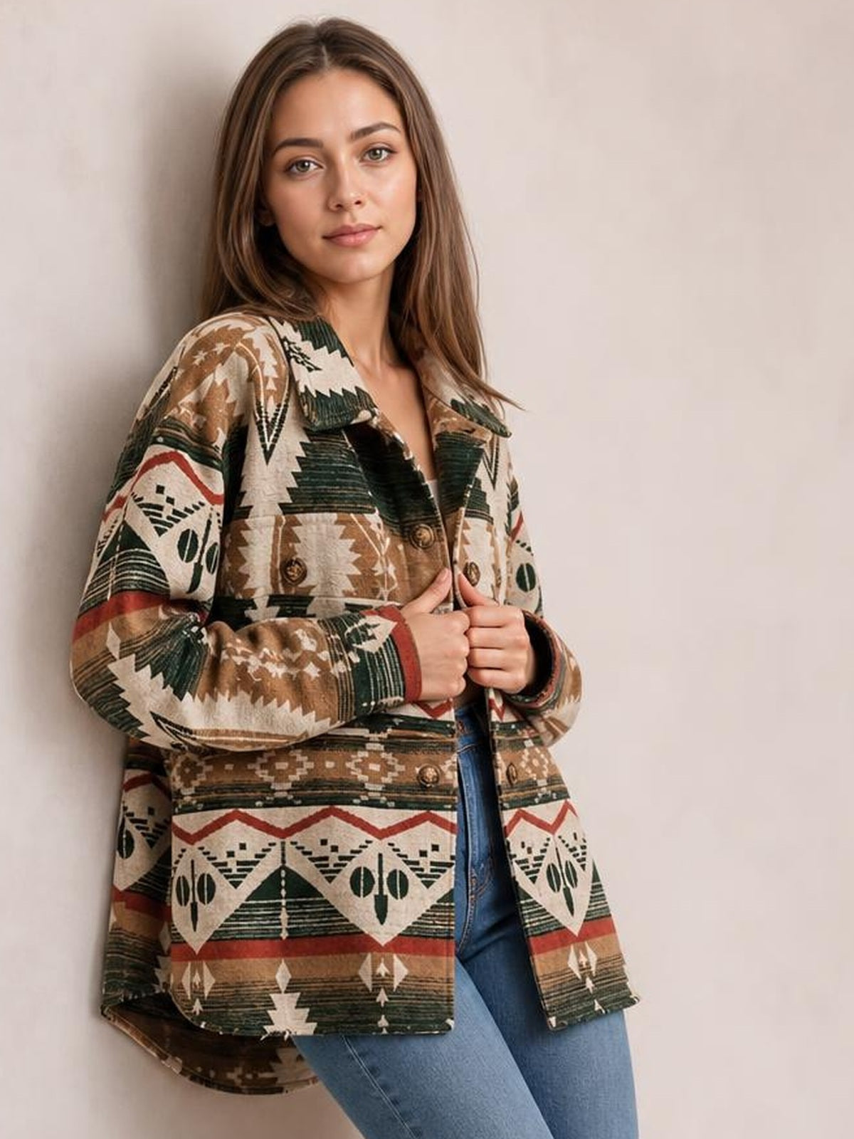 Woman holding a geometric button-up long-sleeve jacket in brown, cream, green, and red, featuring a relaxed long silhouette, lapels, and front pockets.