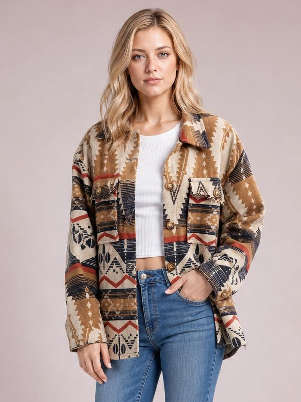 Model poses in a geometric beige, brown, black, and red button-up long sleeve jacket with a collared design, patch pockets, and relaxed silhouette.