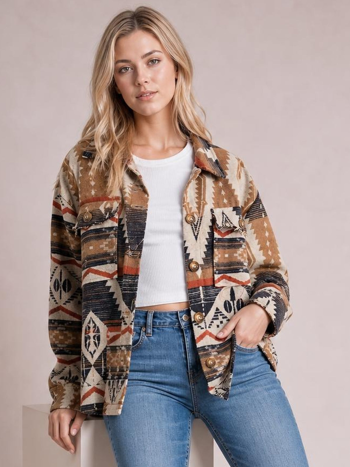 Model wearing a geometric button-up long sleeve jacket in brown, cream, black, and rust with a relaxed silhouette, front buttons, and chest pockets.