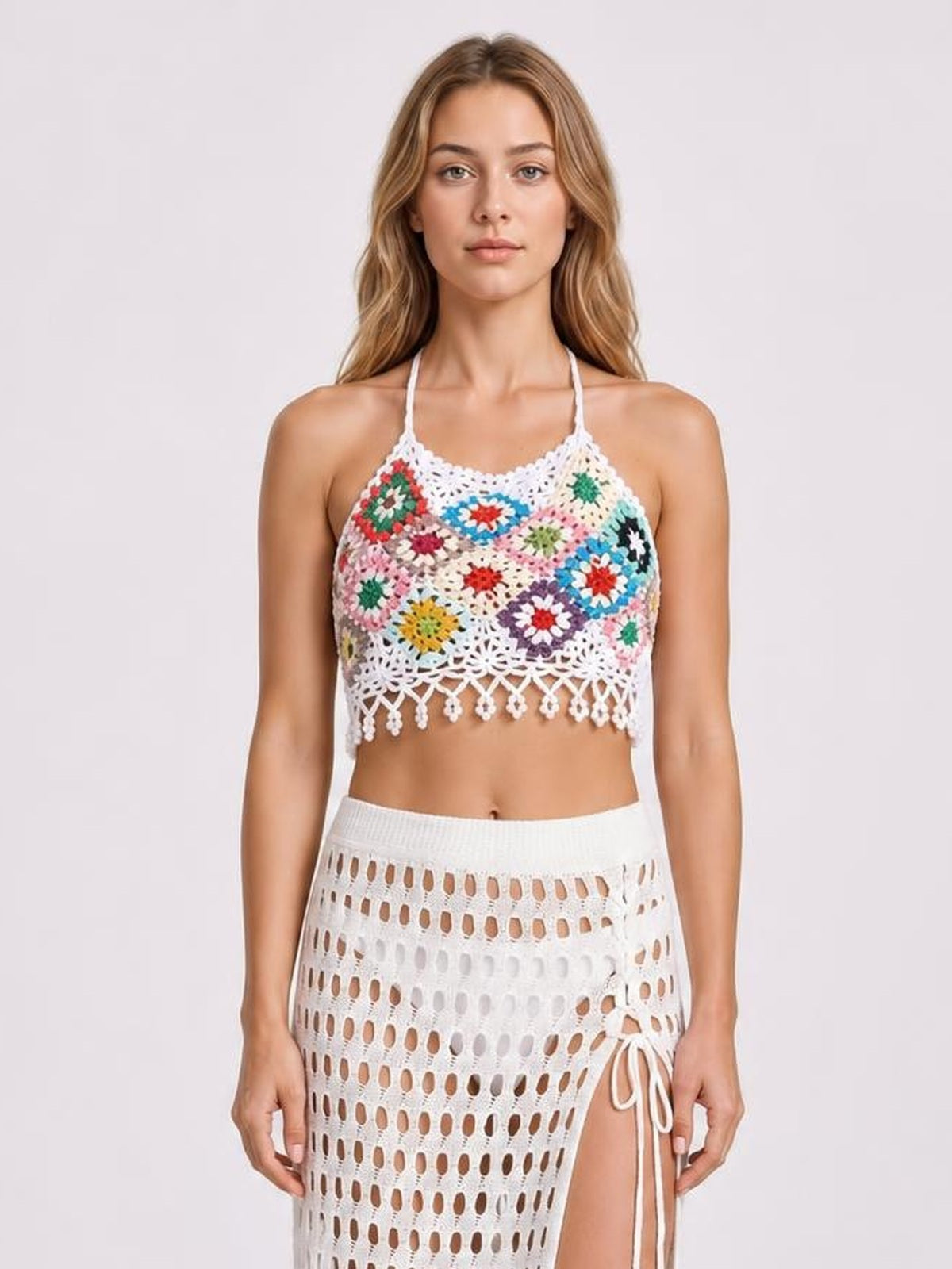 Front-facing model wears a multicolored geometric crochet halter neck swim top with a fitted cropped silhouette, openwork construction, and decorative fringed hem.