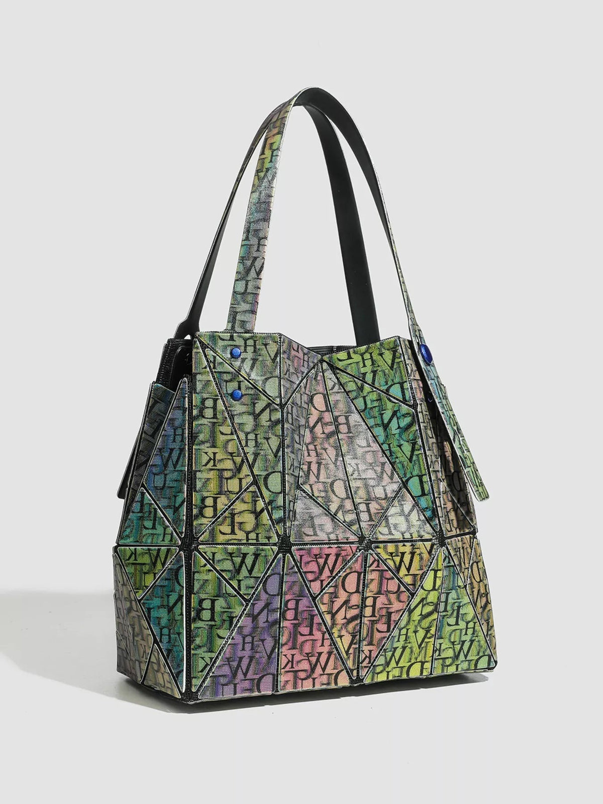 Medium PVC shoulder bag with an iridescent multicolor geometric panel design, structured trapezoid silhouette, black trim, and long shoulder straps.