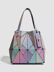 Medium PVC shoulder bag with a structured silhouette, iridescent pink, blue, and silver geometric panels, long straps, and blue stud accents.