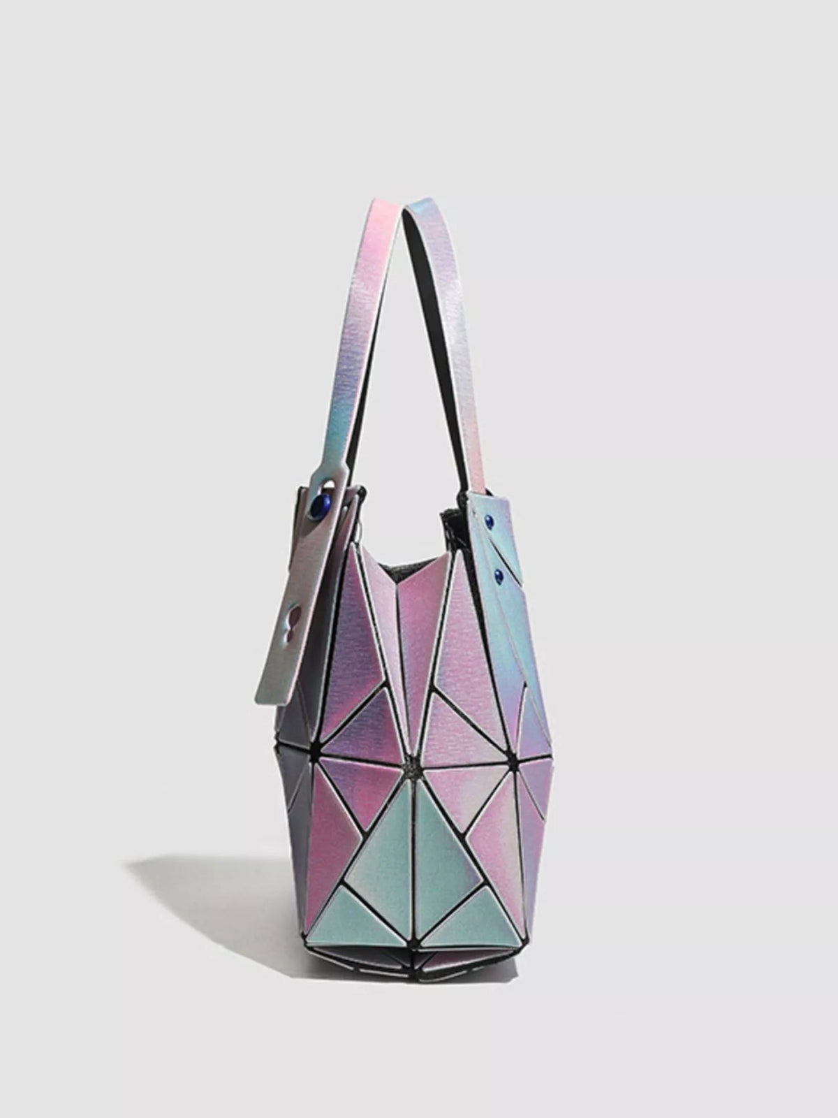 A medium PVC shoulder bag features an iridescent pink, blue, and silver finish, geometric triangular panels, a structured silhouette, and a long shoulder strap.