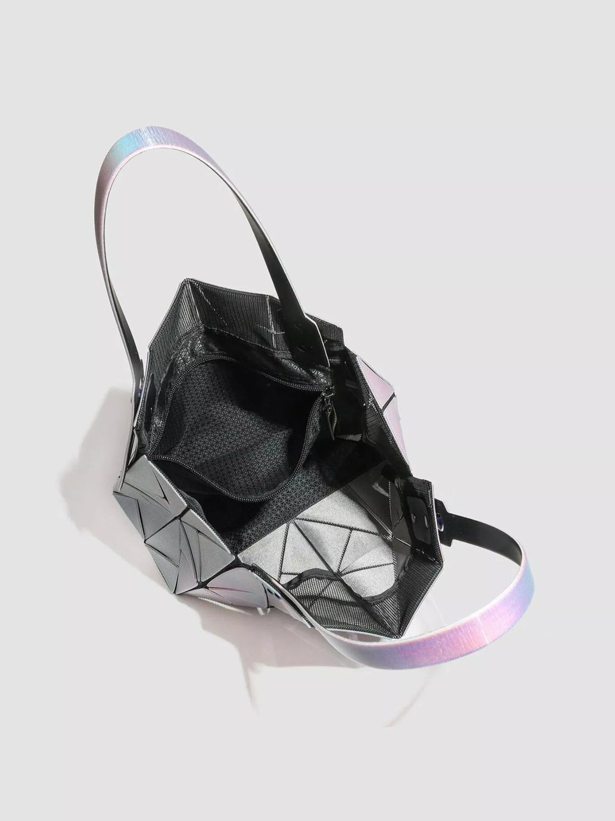 Open medium geometric iridescent PVC shoulder bag with a faceted silver exterior, black textured interior, structured construction, and long strap.
