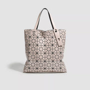Medium blush-pink PVC handbag with a geometric black lattice pattern, structured tote silhouette, open top, and two long handles.