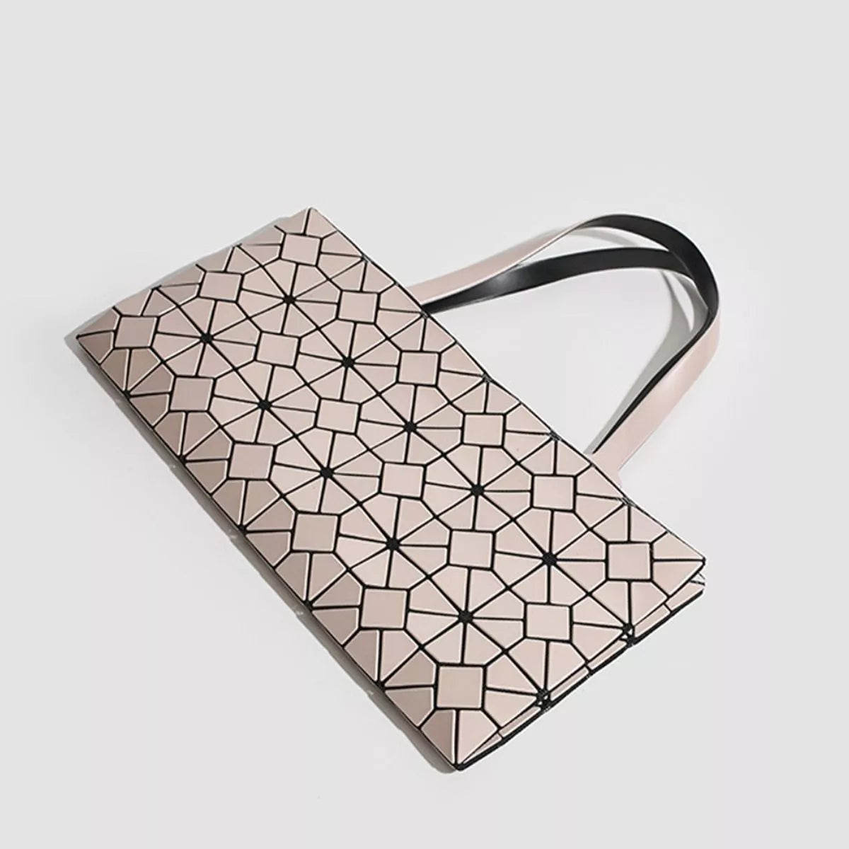 A medium PVC handbag features a pale pink geometric lattice pattern, rectangular silhouette, and long contrasting black-and-pink shoulder handles.