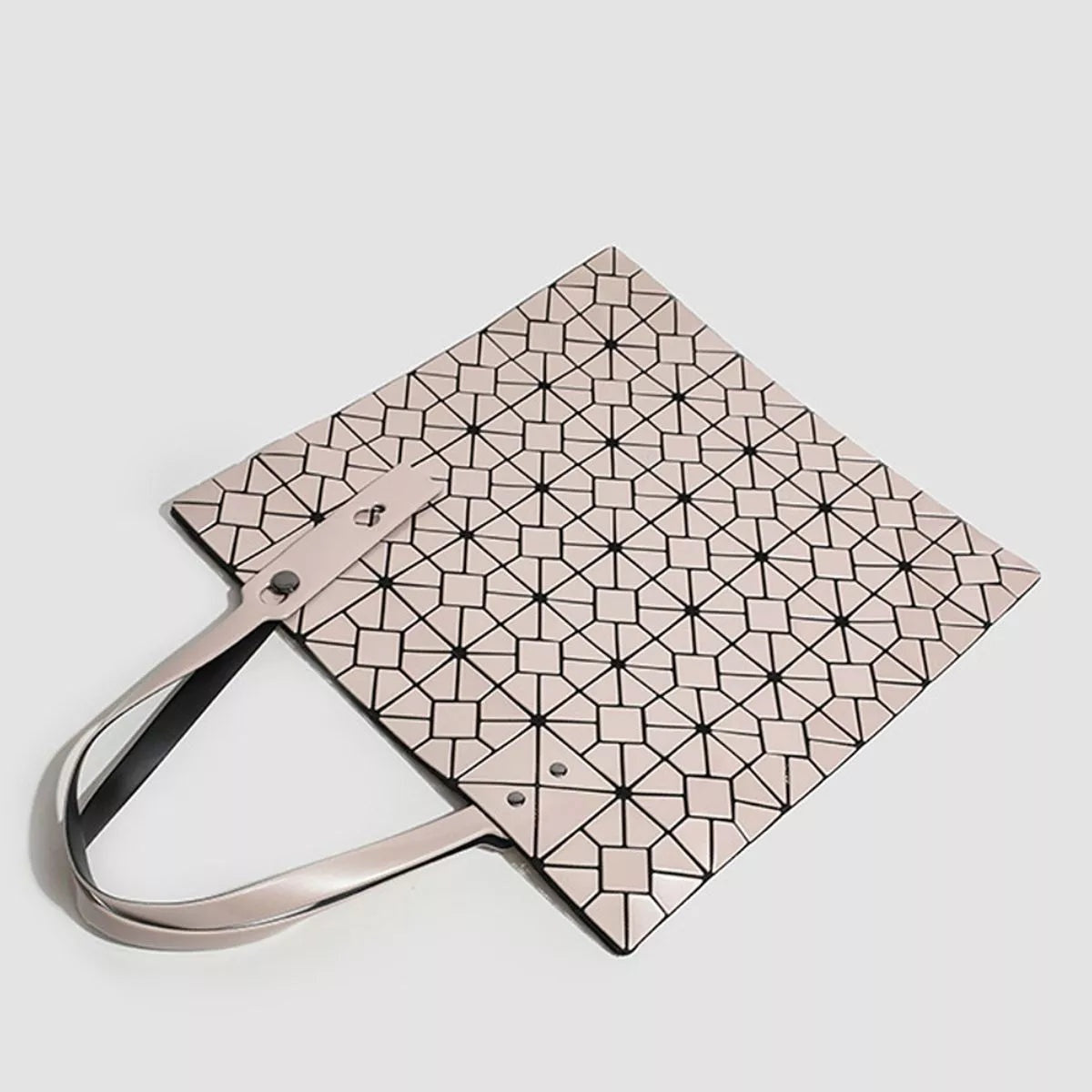 A medium PVC handbag with a structured rectangular silhouette, pale blush finish, black geometric lattice pattern, and slim matching handles.