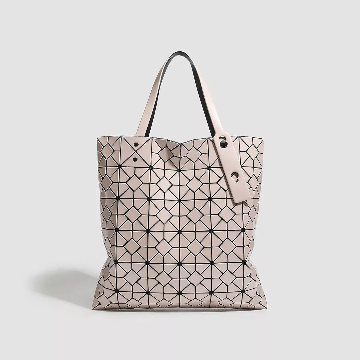 A medium PVC tote handbag features a pale blush geometric lattice pattern, structured rectangular silhouette, twin handles, and visible metal rivet details.