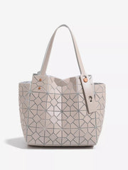 A medium structured PVC handbag in pale beige features a geometric lattice pattern, spacious tote silhouette, twin handles, and decorative rivet fastening.