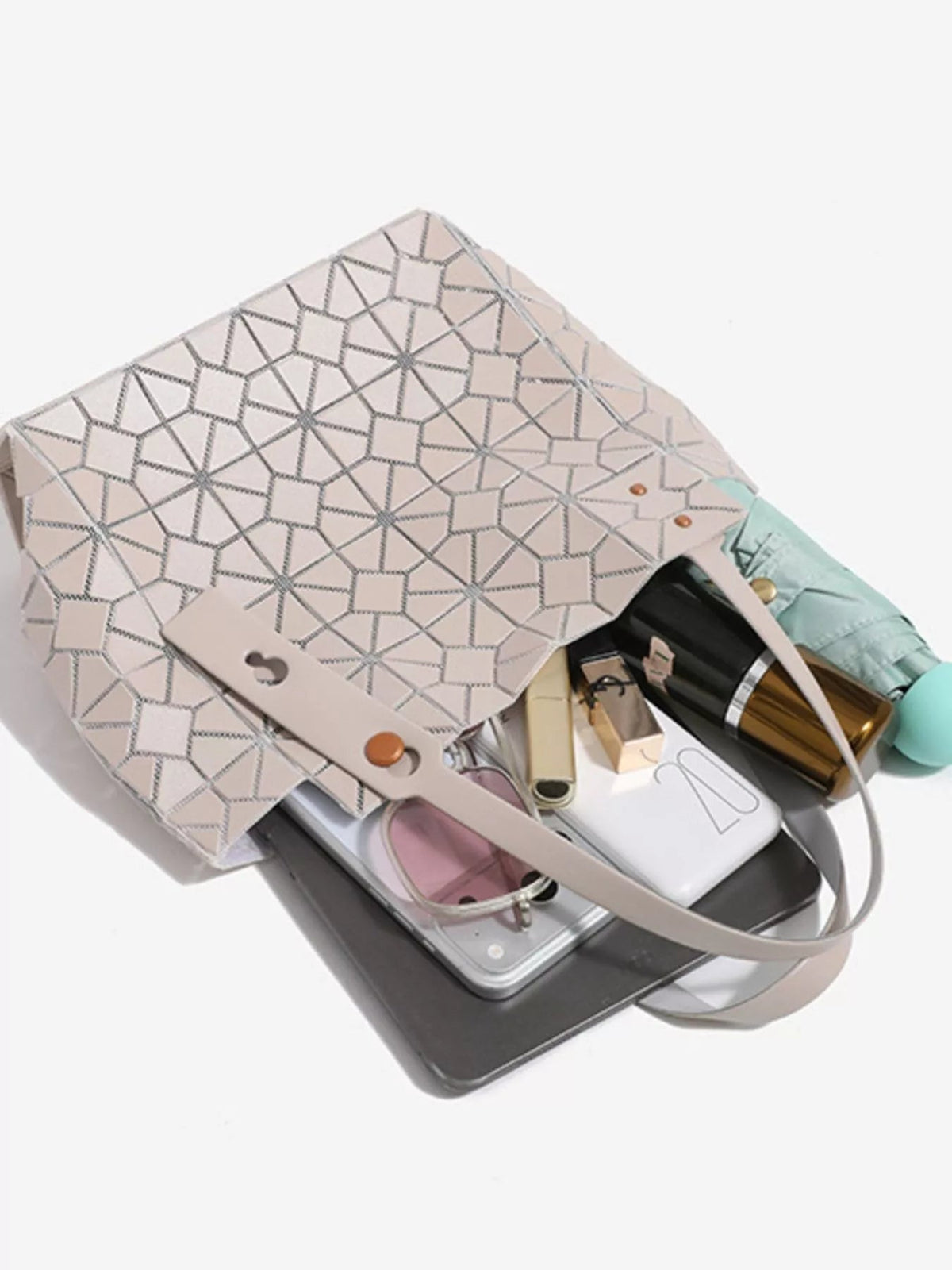 A medium pale blush PVC handbag with a structured silhouette, geometric lattice pattern, twin top handles, and an open interior.