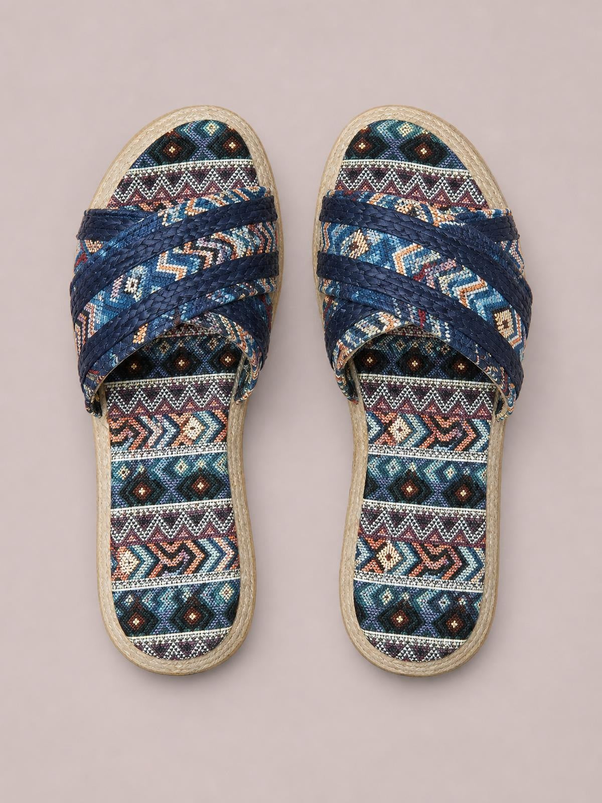 Geometric open-toe platform sandals with navy braided crossover straps, multicolored geometric-patterned footbeds, and flat woven-look soles.