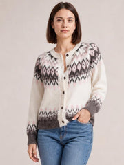 Model wearing a stretchy brushed knit cardigan with a cream base, pink and charcoal geometric pattern, button front, round neck, long sleeves, and ribbed trim.