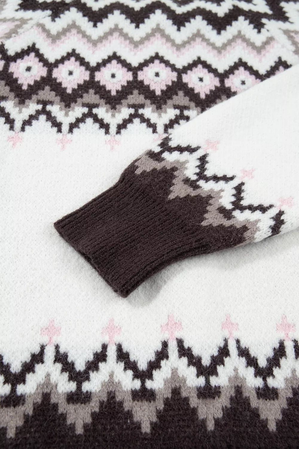 Close-up of a brushed knit cardigan showing a black, white, gray, and pink geometric pattern with a ribbed black cuff and soft textured construction.