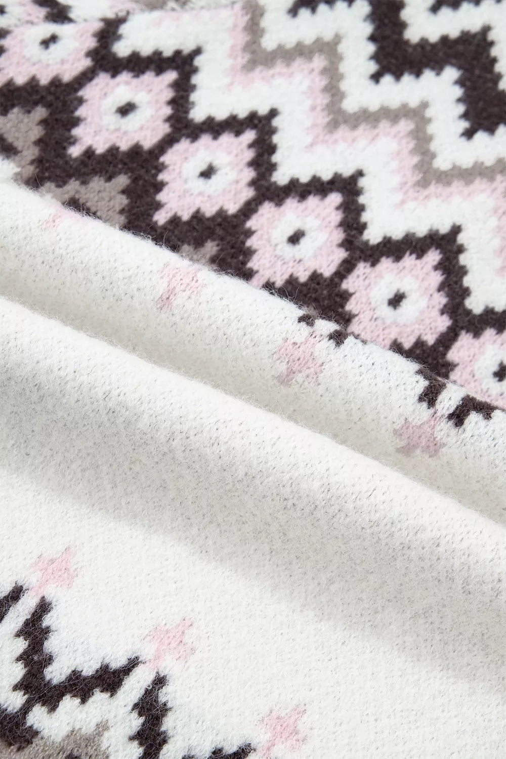 Close-up of a soft brushed knit cardigan in white with black, gray, and pink geometric floral motifs, highlighting its fuzzy textured construction.