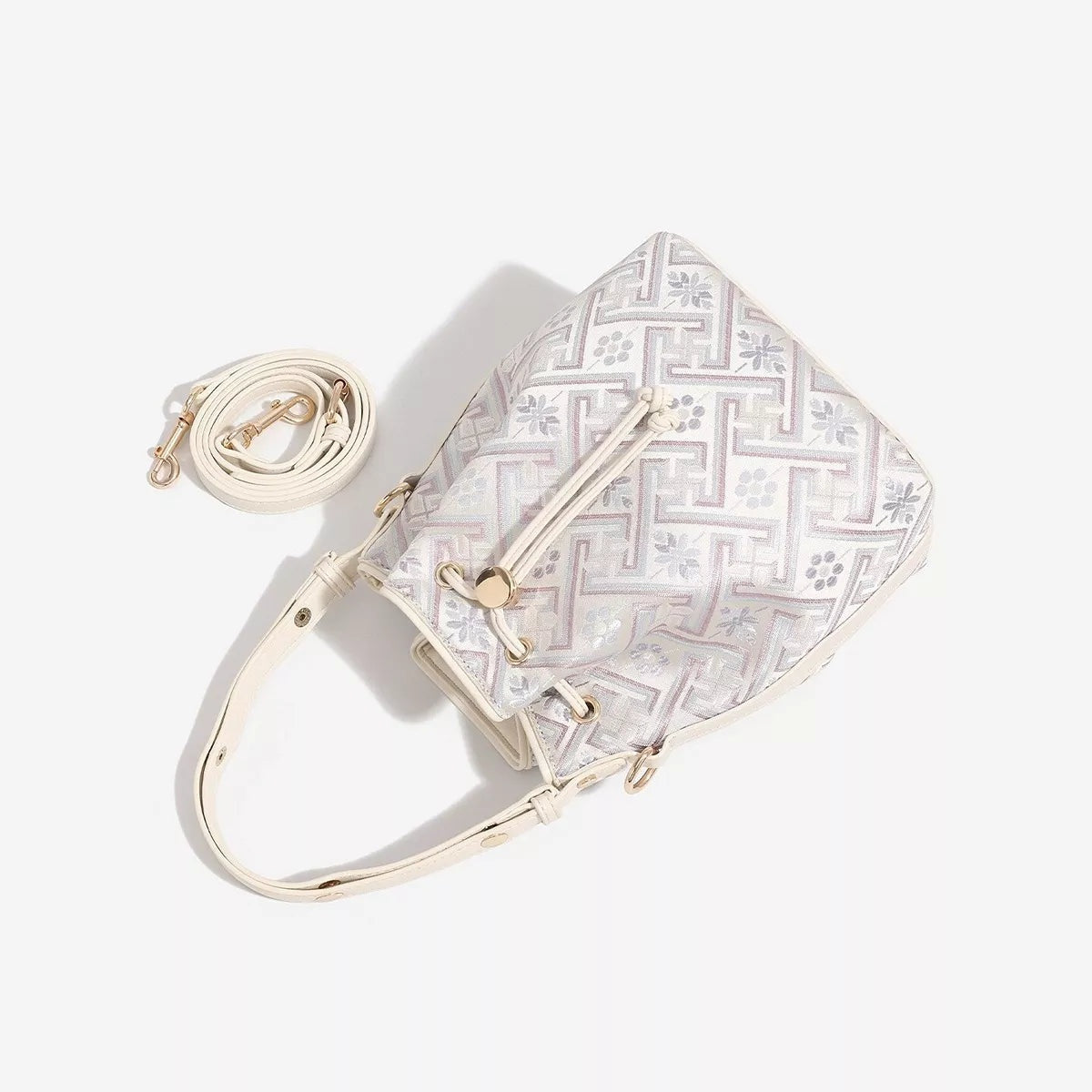 Small light-colored PU leather bucket bag with a geometric pattern, drawstring closure, gold-tone hardware, and a long crossbody strap.