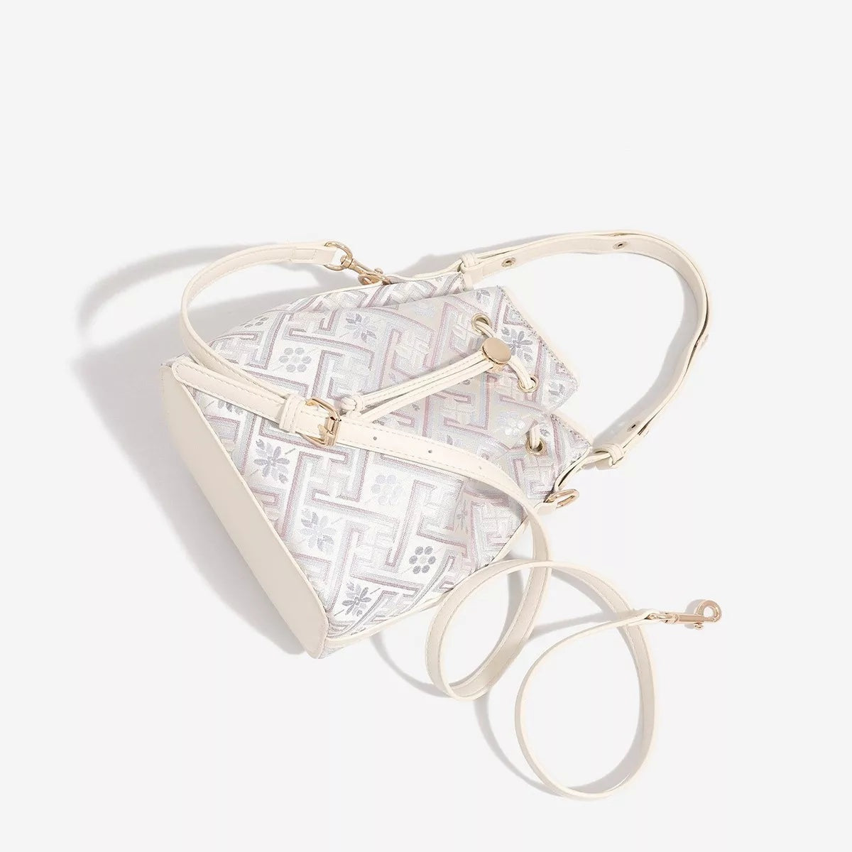 Small ivory PU leather bucket bag with a geometric pattern, drawstring closure, short top handle, and long crossbody strap.