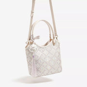 Small ivory polyester handbag with a geometric patterned body, floral accents, double top handles, and a long adjustable shoulder strap.