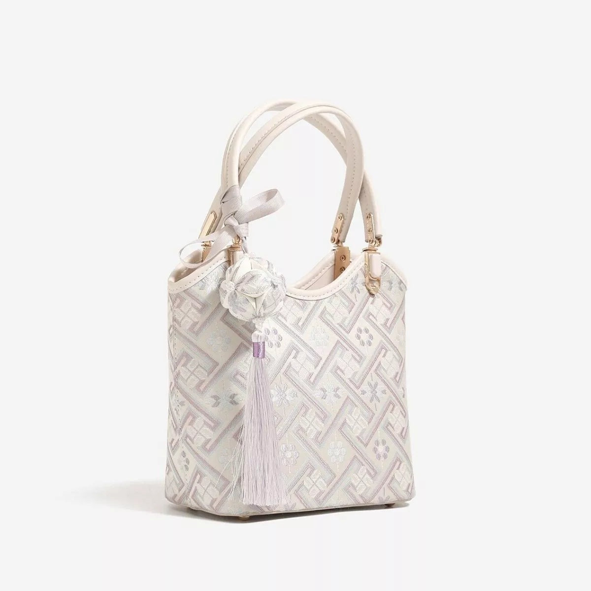 Small cream polyester handbag with a geometric pattern, twin top handles, gold-tone hardware, and a structured bucket silhouette.