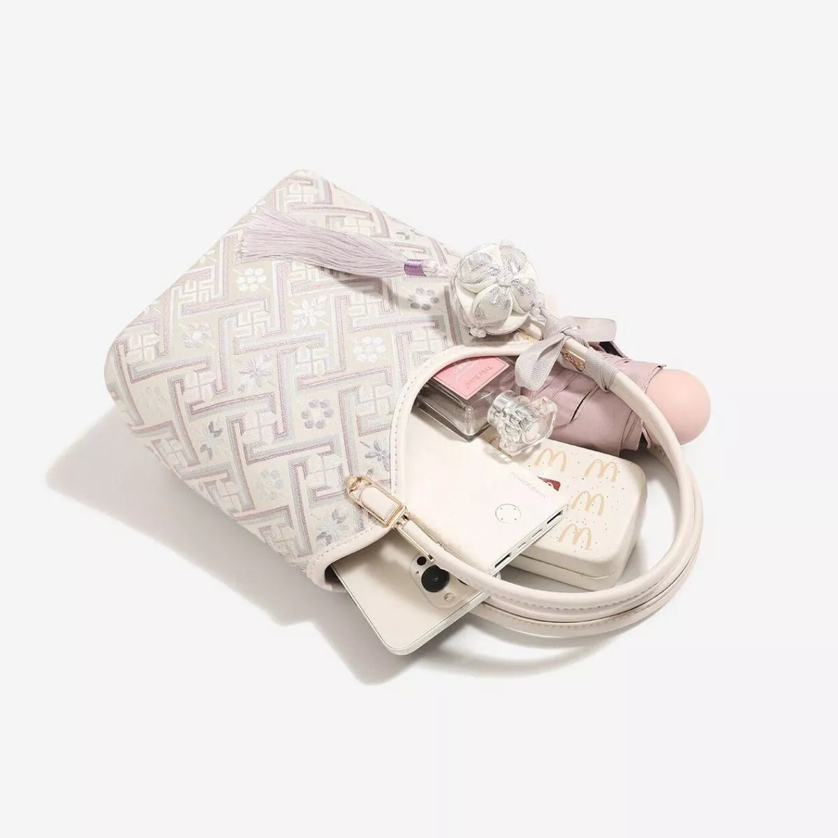 Small pastel pink and cream polyester handbag with a geometric pattern, twin rounded handles, and a softly structured silhouette.