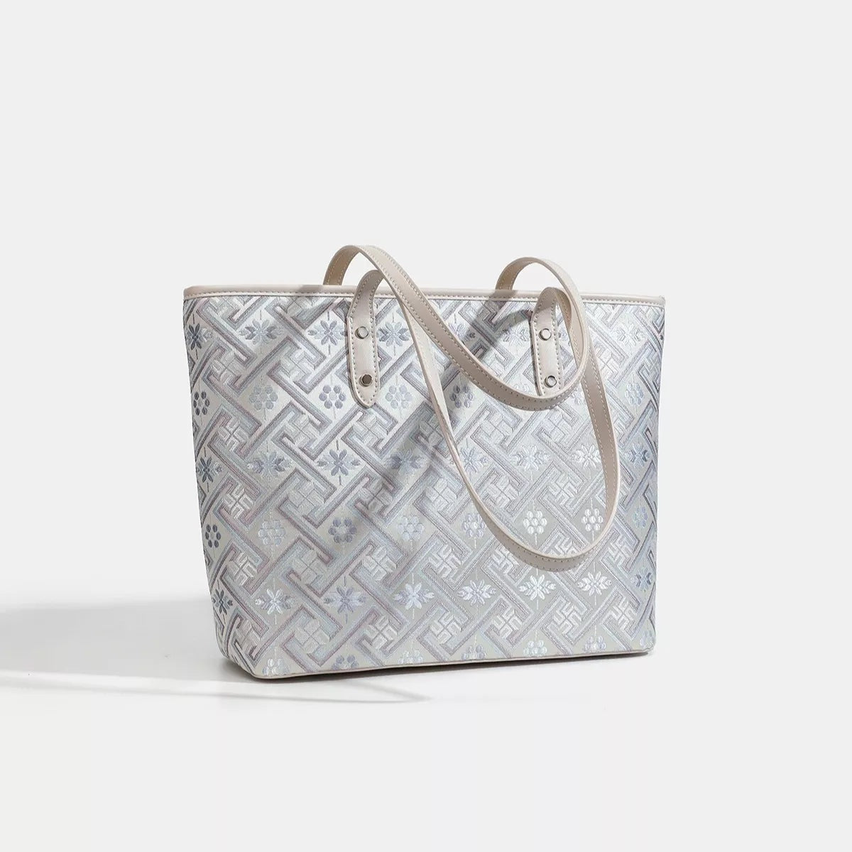 Medium faux leather tote bag with a structured rectangular silhouette, cream and gray geometric pattern, twin rolled handles, and a clean flat base.