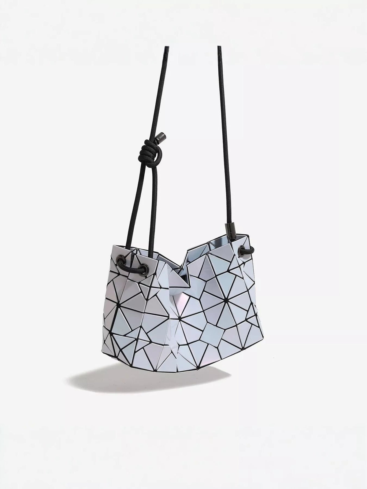 Small geometric prism iridescent PVC shoulder bag with faceted white panels, black outlined construction, and long rope straps with a knotted detail.