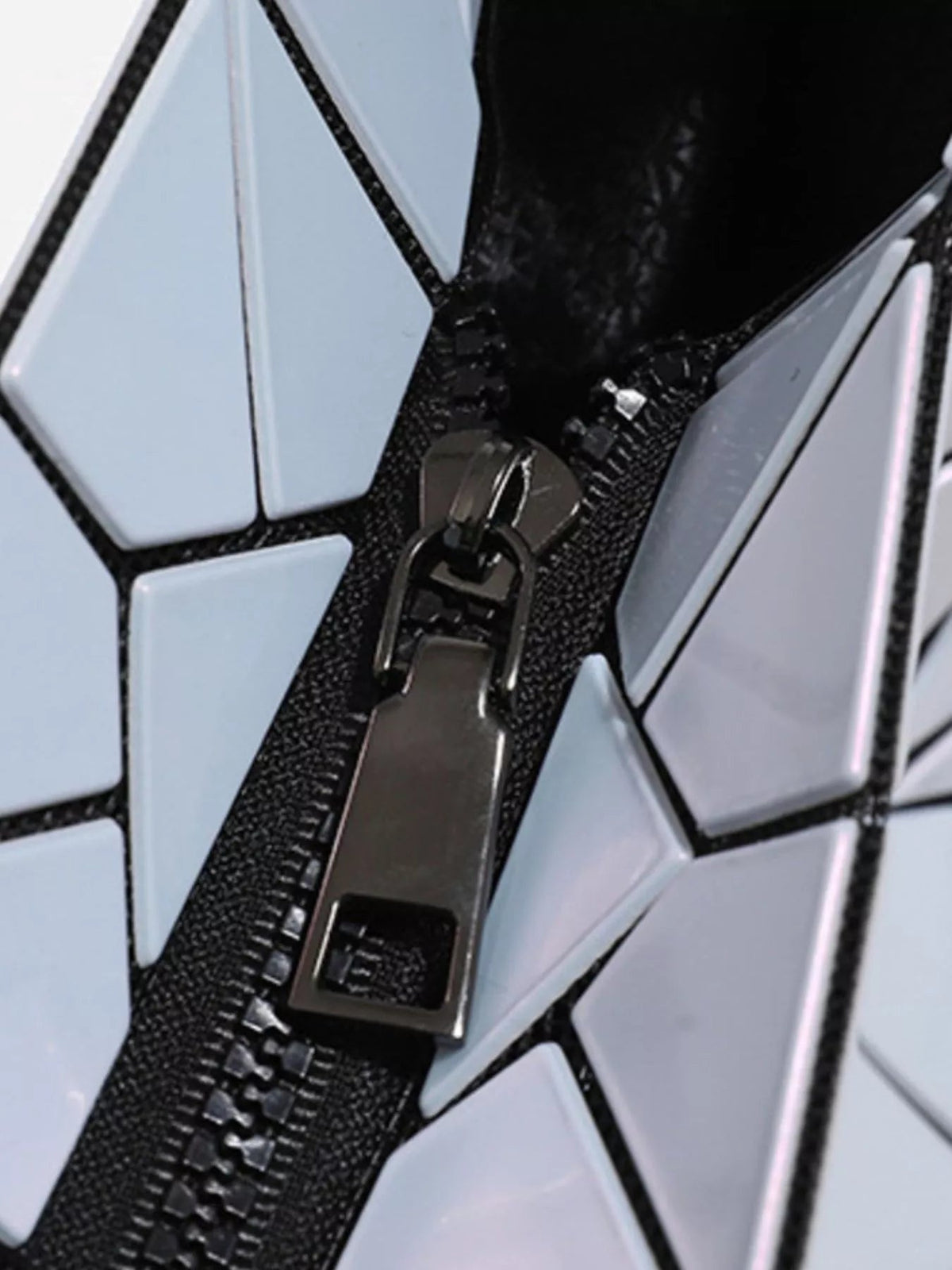 Close-up of a small geometric prism iridescent shoulder bag with pale blue PVC panels, black textured trim, and a metal strap attachment.