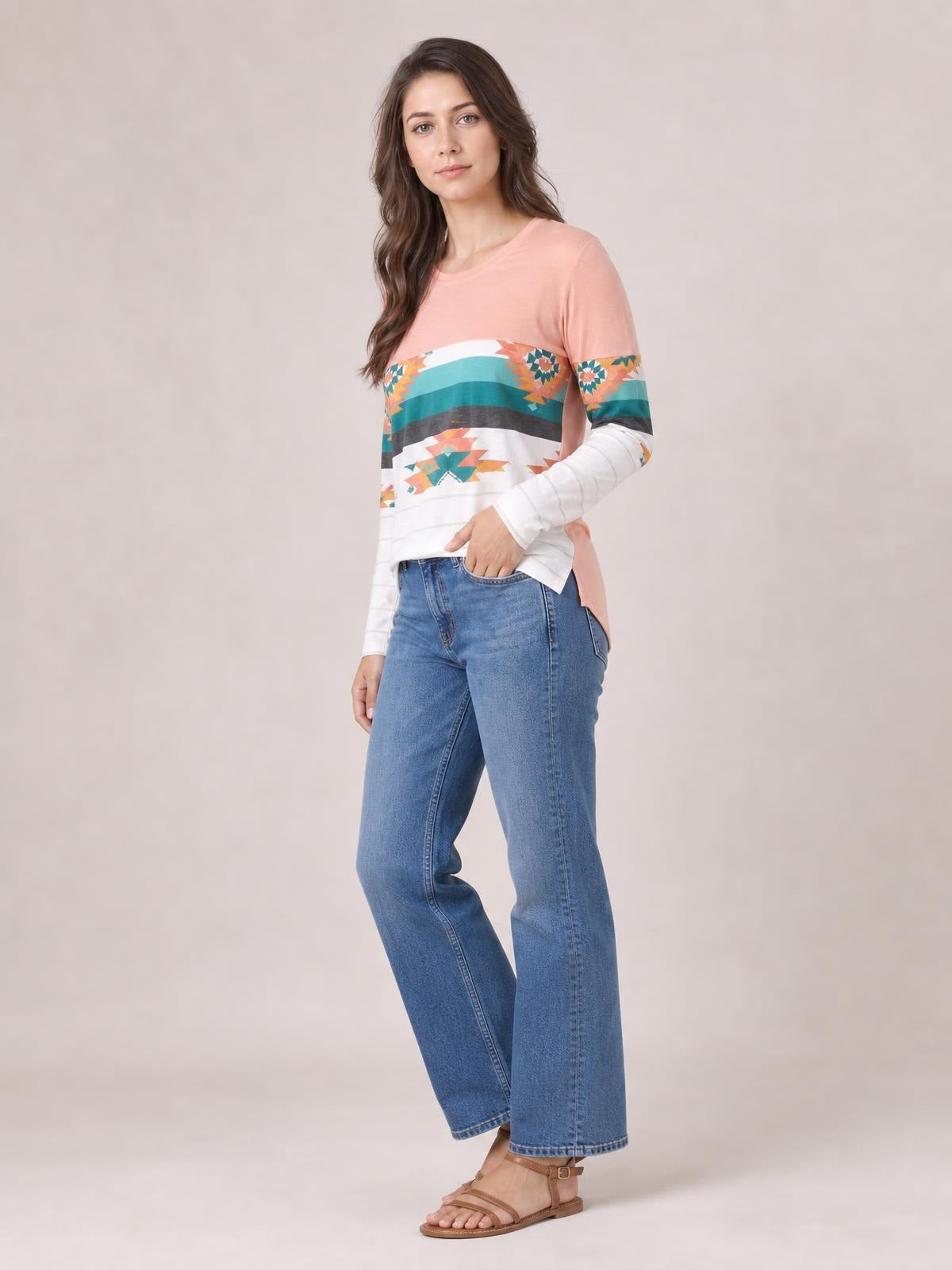 Model poses in a geometric round-neck long-sleeve T-shirt with a pink upper body, striped floral print, white sleeves, and a relaxed silhouette.