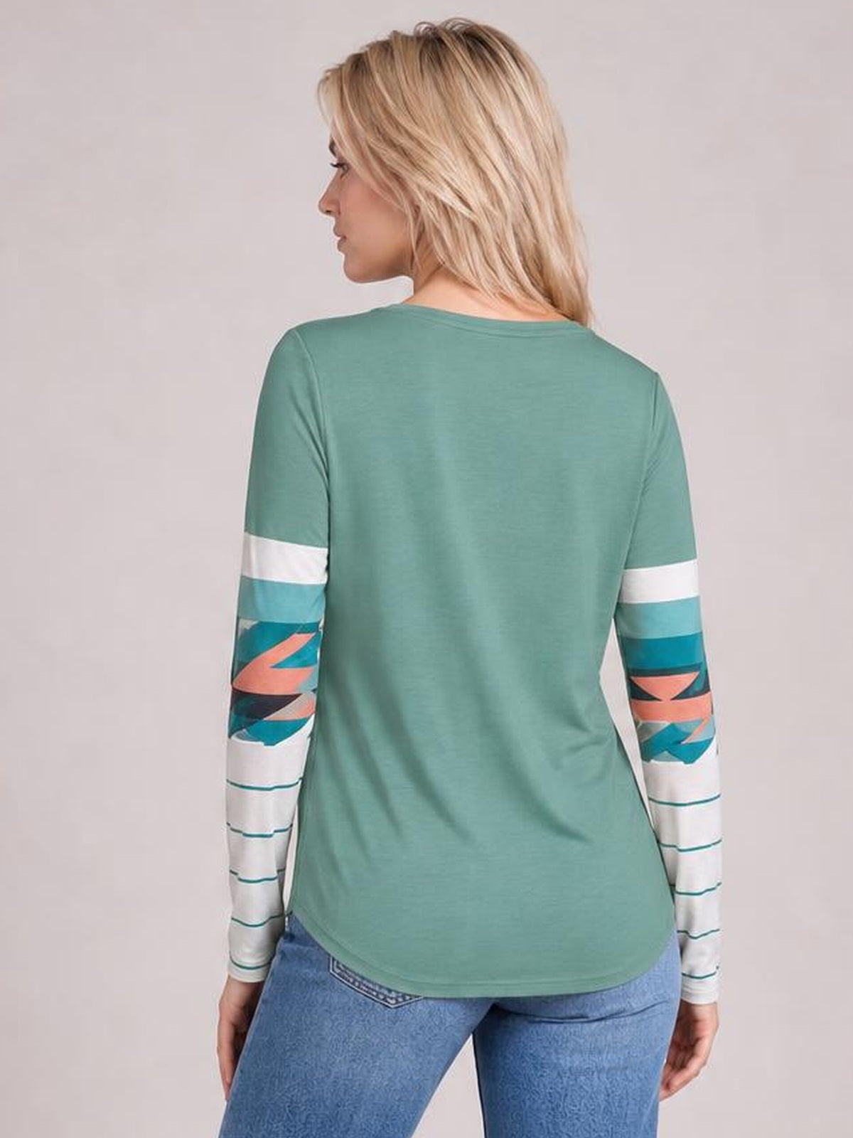 A model shows the back of a mint green geometric round neck long sleeve T-shirt with a relaxed silhouette and colorful striped graphic sleeves.