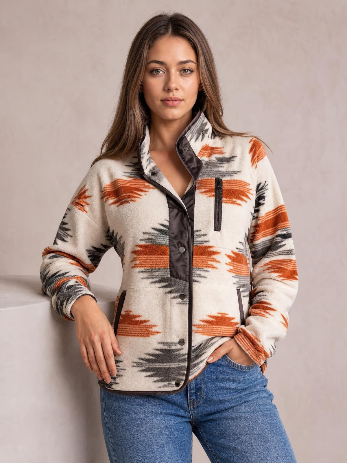 Model poses in a cream Geometric Snap Down Jacket with orange and black geometric stripes, a structured collar, snap-front closure, long sleeves, and front pockets.