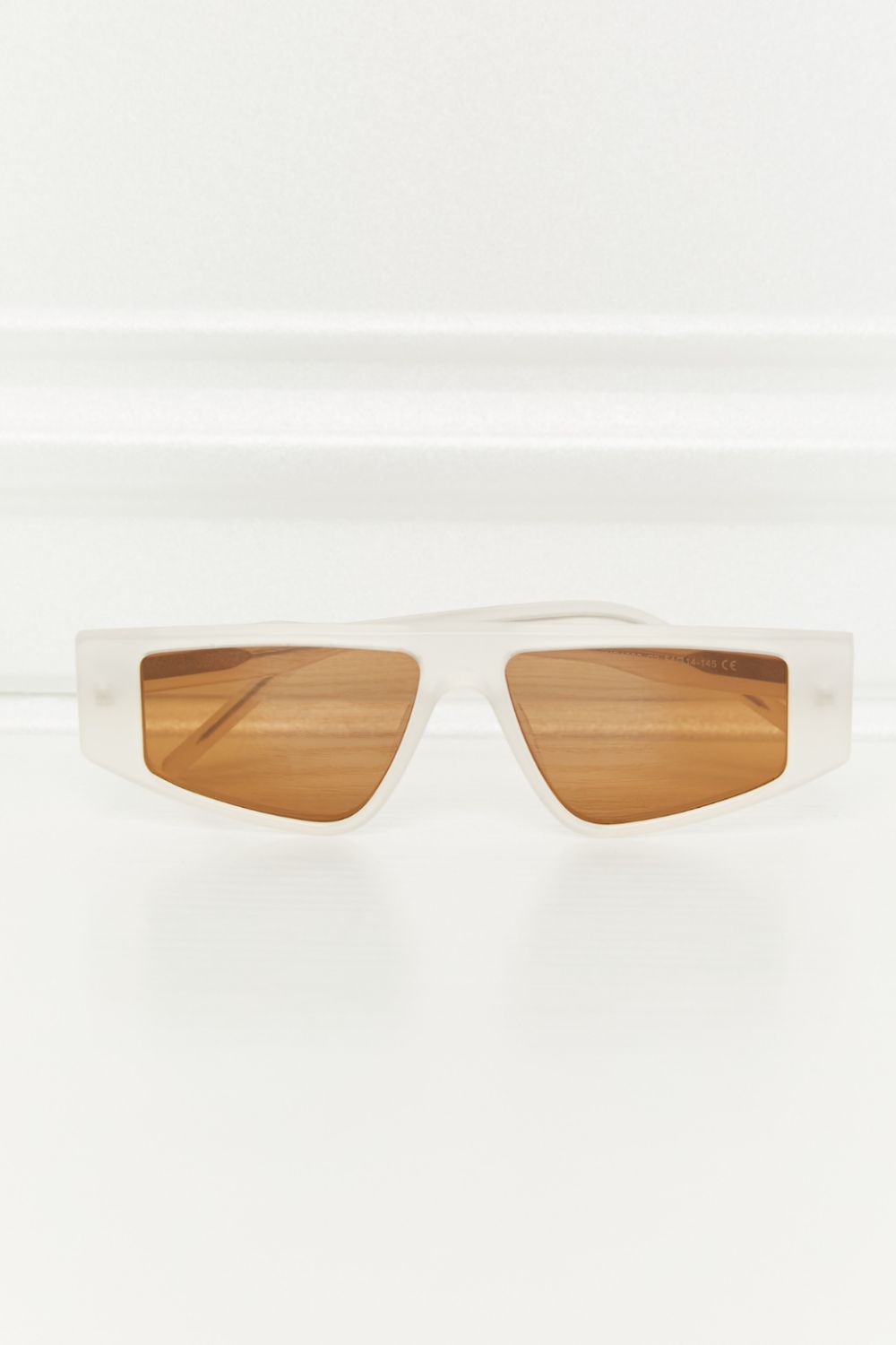 Geometric TAC polarized sunglasses feature a structured ivory acetate frame and warm caramel lenses in a sleek, angular silhouette.