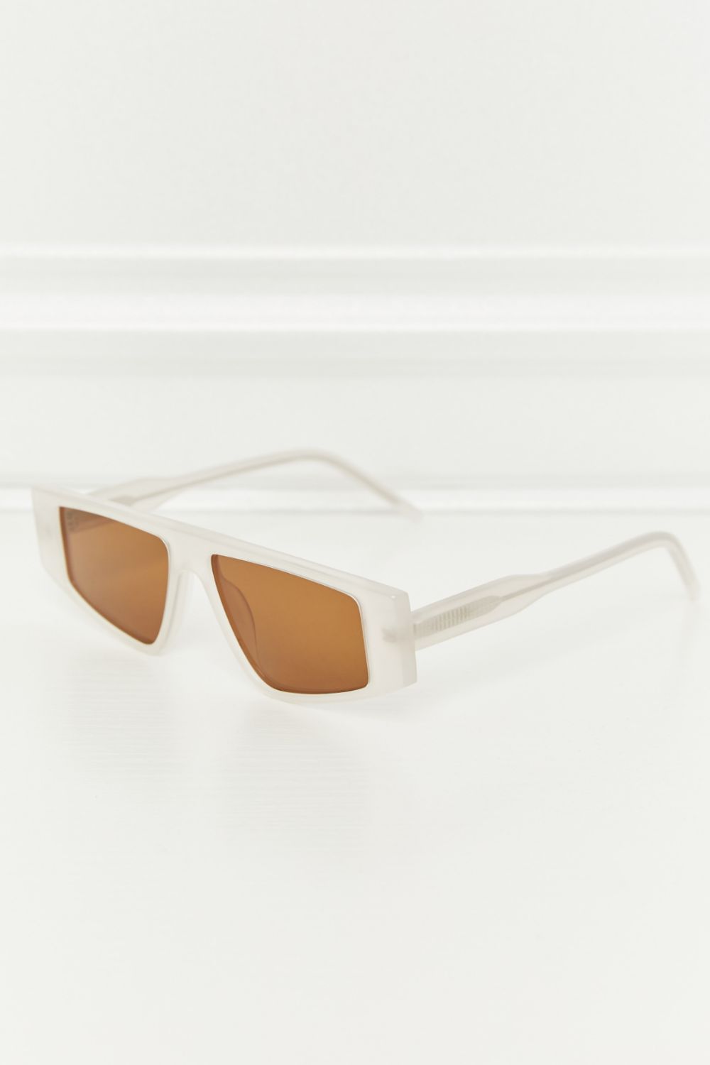 Geometric acetate sunglasses feature a structured translucent caramel frame, slim temples, and rich brown TAC polarized lenses for a polished modern silhouette.