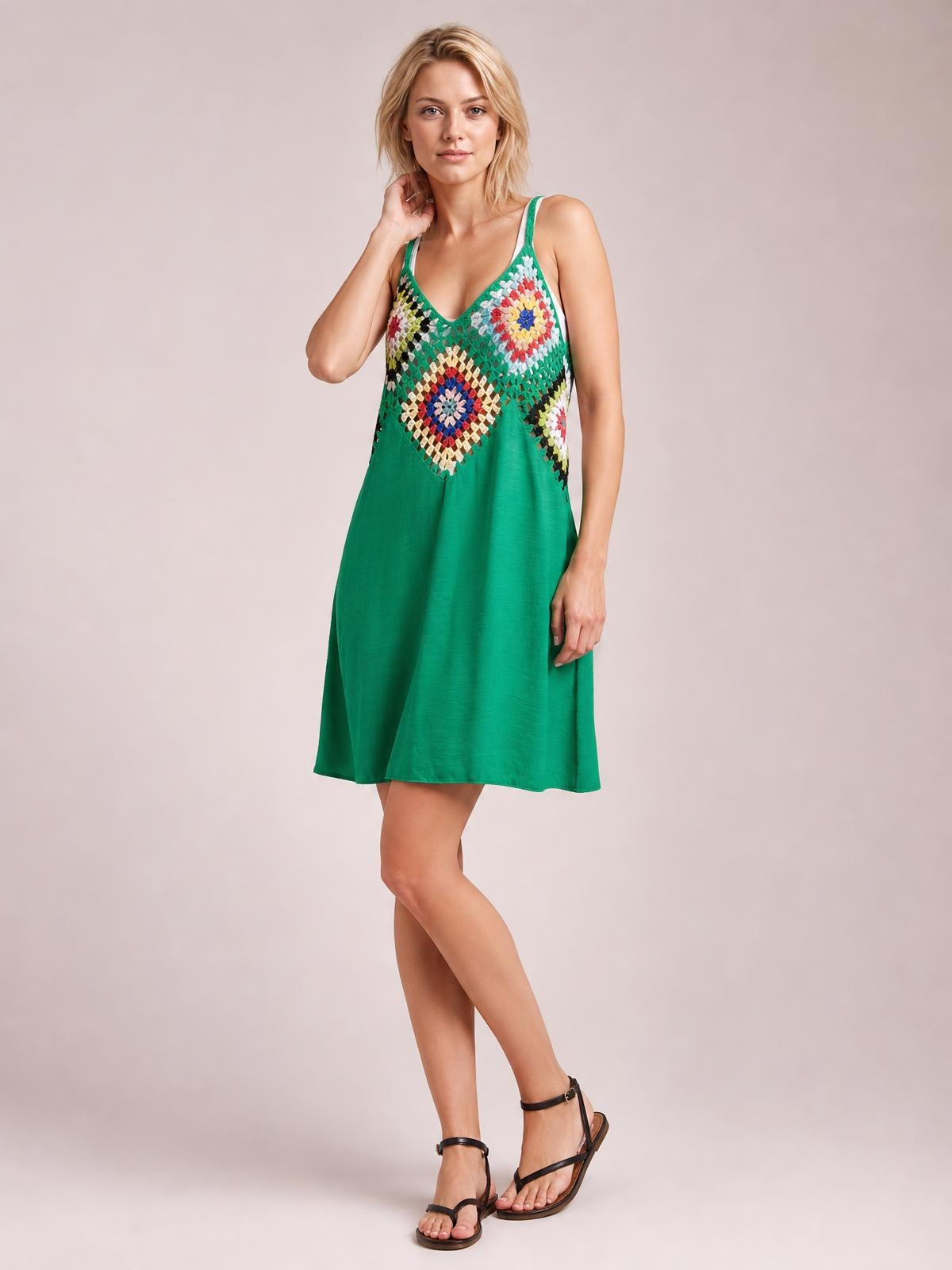 Model poses with one hand near her hair in a green geometric V-neck spaghetti strap cover-up dress with a relaxed, semi-sheer A-line silhouette.