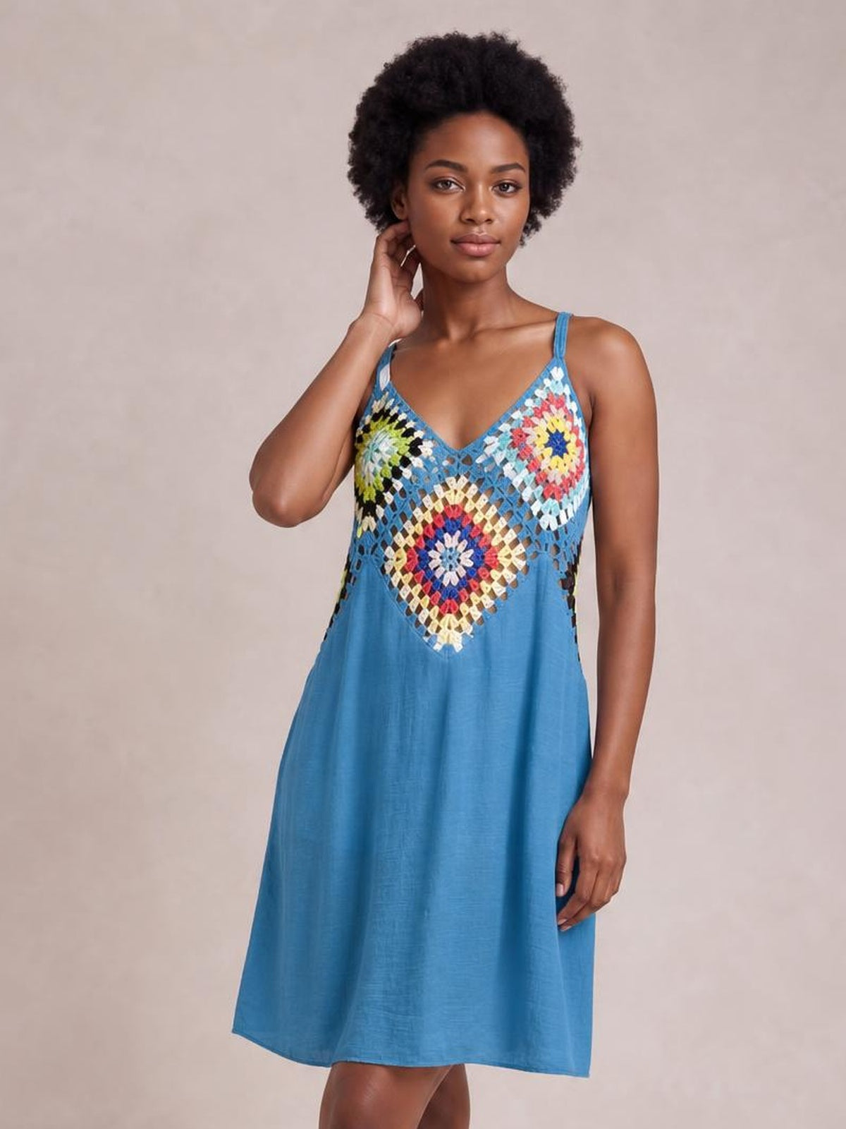 A model poses with one hand at her neck in a blue geometric V-neck spaghetti strap cover-up dress with a loose, above-knee silhouette.