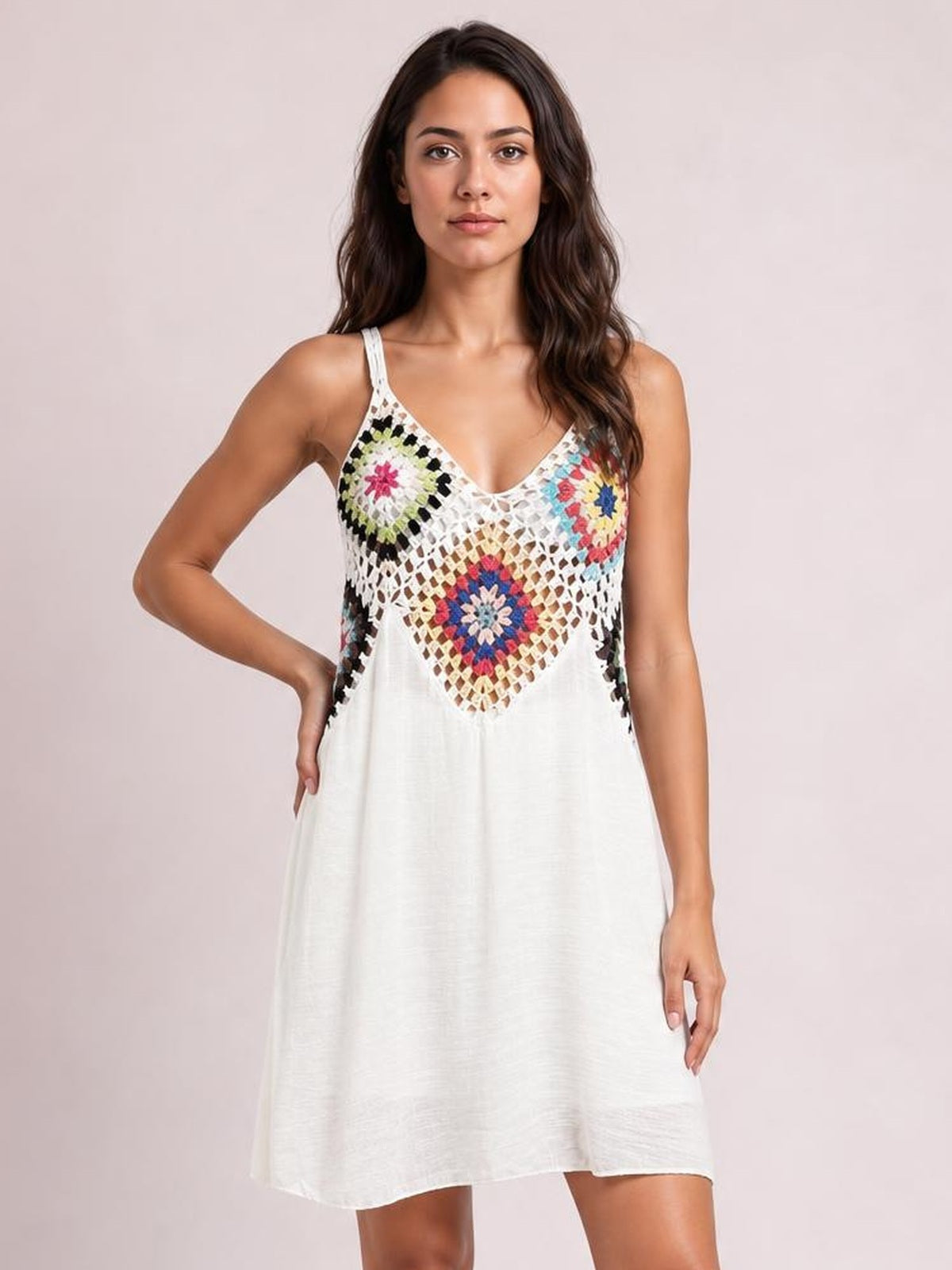 Model poses with one hand on her hip in a white semi-sheer geometric V-neck spaghetti strap cover-up dress with colorful patterned panels and a loose short silhouette.