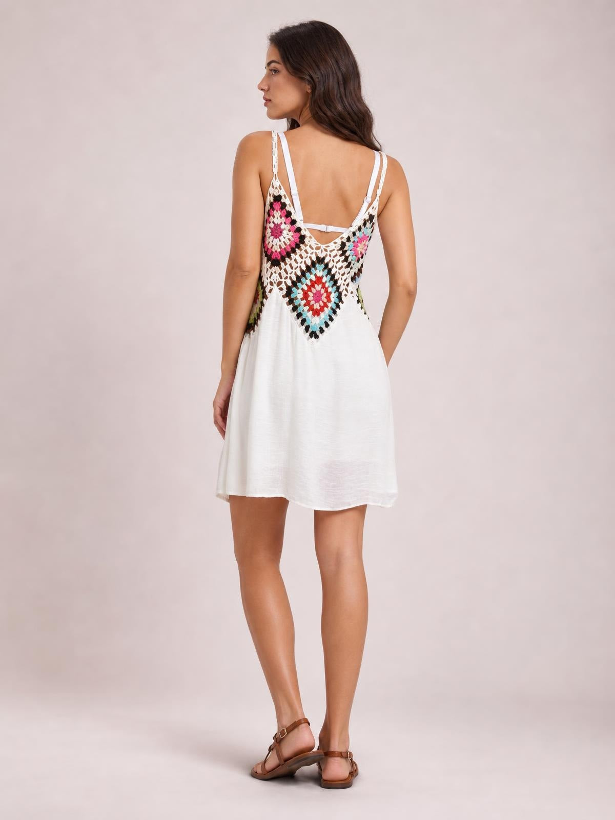 A model looks over her shoulder in a white spaghetti-strap cover up dress with a colorful geometric back panel and relaxed, short A-line silhouette.