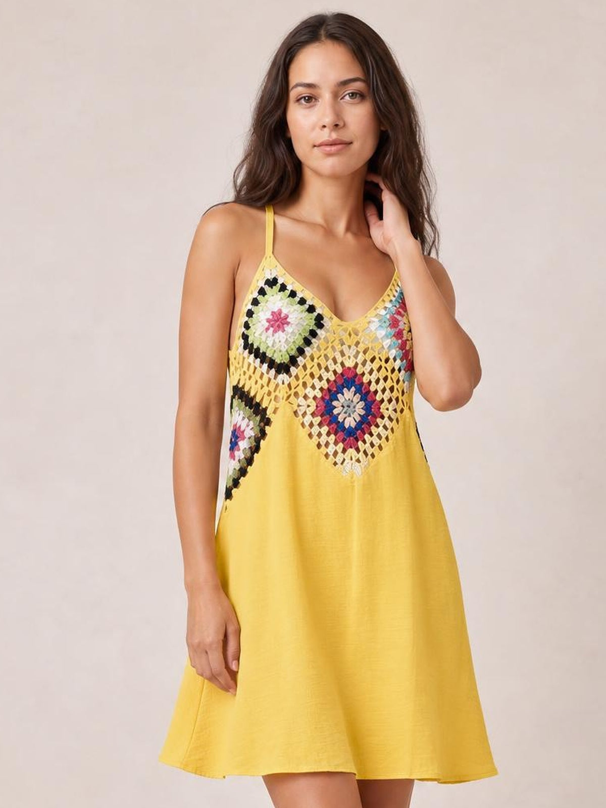 Model poses with one hand near her neck in a yellow geometric V-neck spaghetti strap cover-up dress with a semi-sheer patterned bodice and relaxed A-line silhouette.
