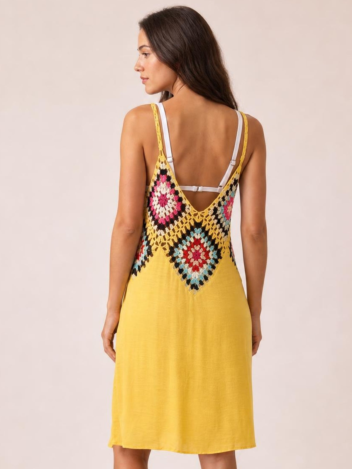 Model shown from the back in a yellow spaghetti-strap cover-up dress with a colorful geometric openwork panel and relaxed straight silhouette.