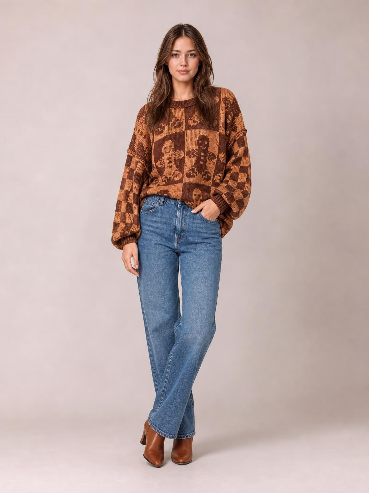 Model wearing a brown gingerbread man sweater with a round neck, drop shoulders, patterned knit construction, relaxed silhouette, and one hand in a pocket.