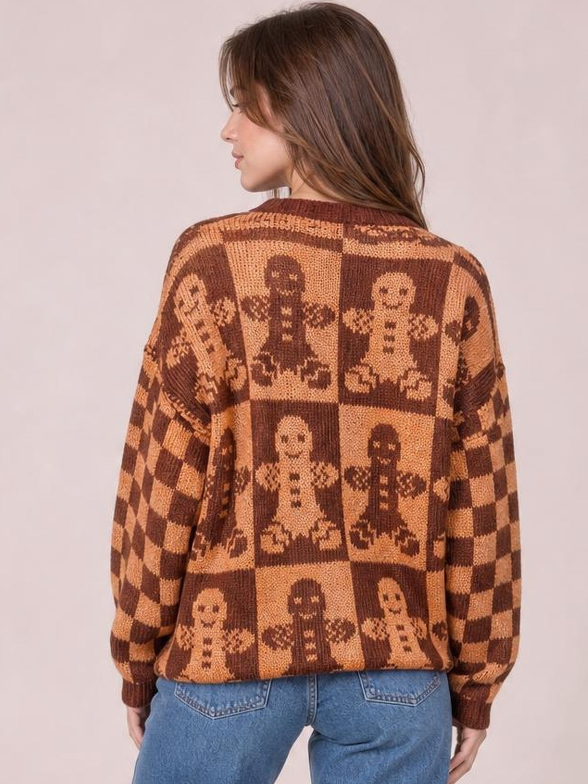 Model shown from the back wears a brown and tan gingerbread man sweater with a round neck, drop shoulders, long sleeves, and a relaxed silhouette.