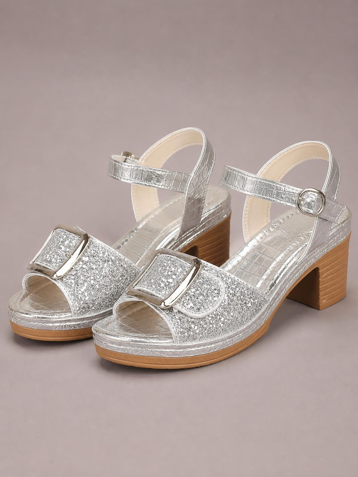 Silver glitter sandals feature open toes, wide buckle straps, ankle straps, and comfortable mid-height block heels with textured rubber soles.