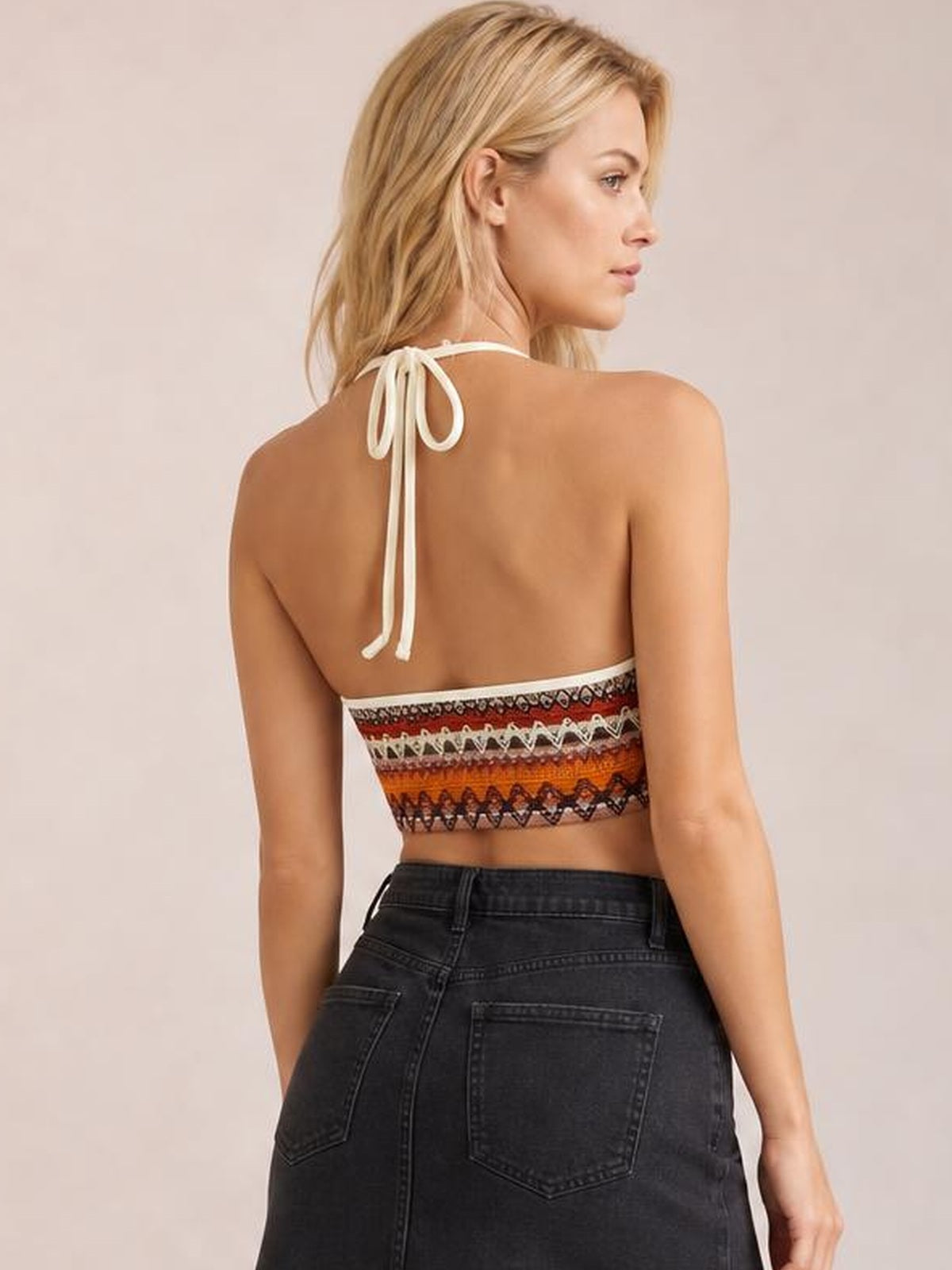 Model turned away in a colorful patterned halter neck short cami with a tied back, cropped silhouette, and exposed shoulders.